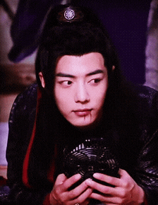 a young man with long black hair is holding a fan in his hands