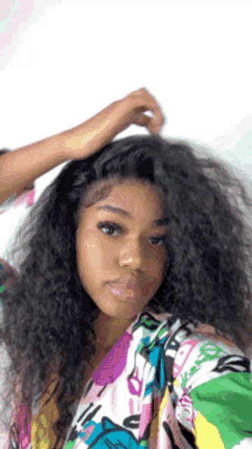 a woman with curly hair is taking a selfie with her phone .