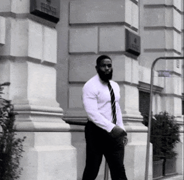 a man in a white shirt and tie walks in front of a building with a sign that says ' french '
