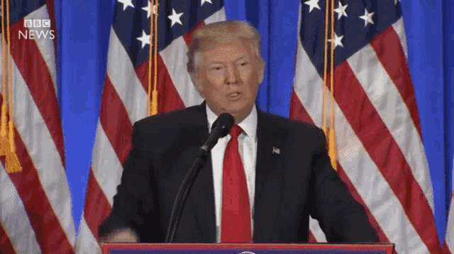 donald trump is giving a speech at a podium in front of an american flag