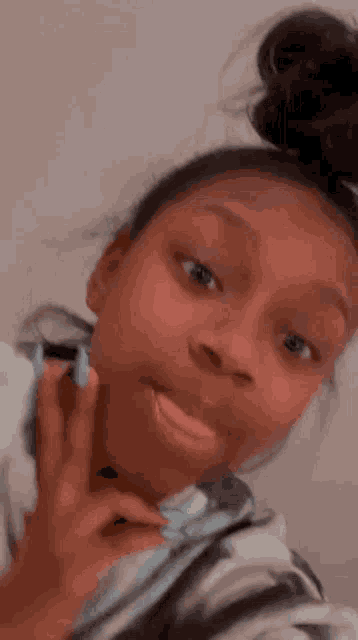 a young girl with blue nails is taking a selfie with her hand on her face .