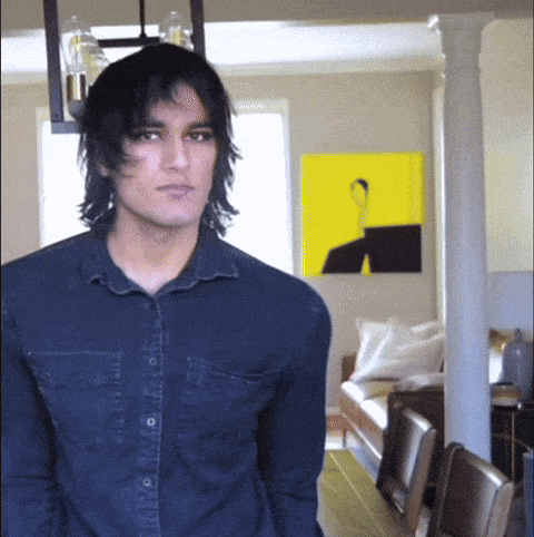 a man in a denim shirt is standing in a living room