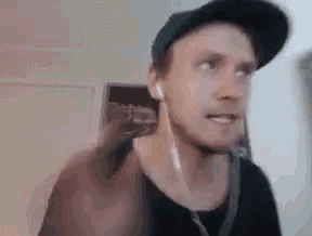 a man wearing a hat and ear buds is talking on a video call .