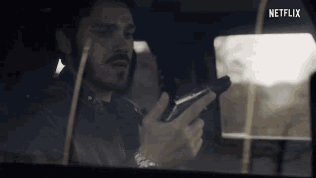 a man in a car holding a gun with netflix written on the bottom right