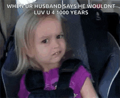 a little girl is sitting in a car seat with a funny face .