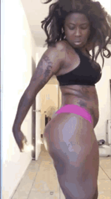 a woman in a black bra and pink underwear is standing in a room .