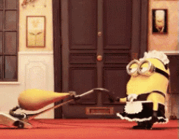a yellow minion dressed as a maid is holding a vacuum cleaner