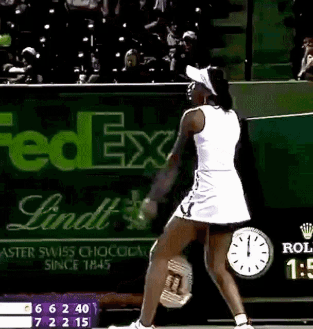 a tennis player is playing in front of a fedex and lindt ad