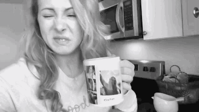 a woman is holding a mug with a picture of a woman on it in a kitchen .