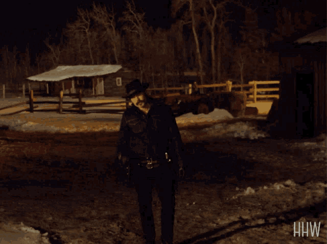 a man in a cowboy hat stands in a snowy area with the letters hw on the bottom right