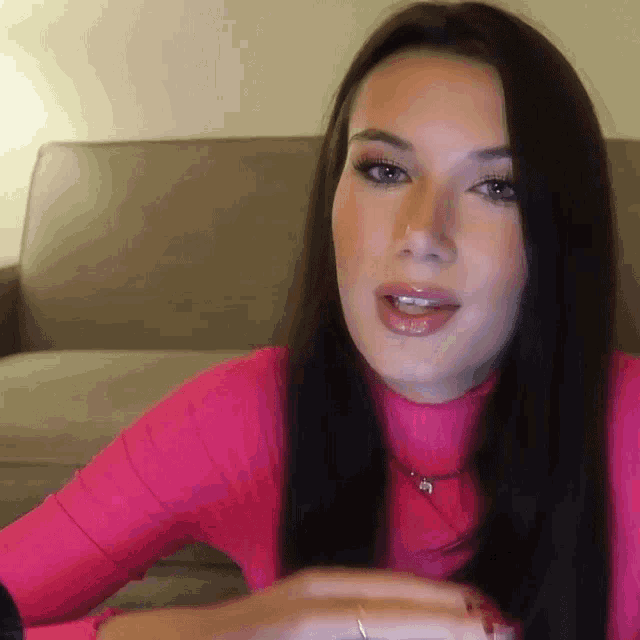 a woman is wearing a pink turtleneck and a necklace