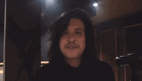 a man with long hair and a mustache is making a funny face