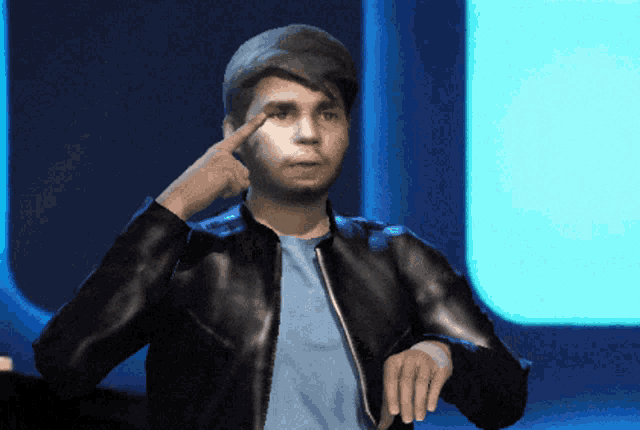 a man wearing a black jacket and a blue shirt points to his eye
