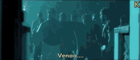 a group of people are standing in a dark room and one of them is talking to another person .