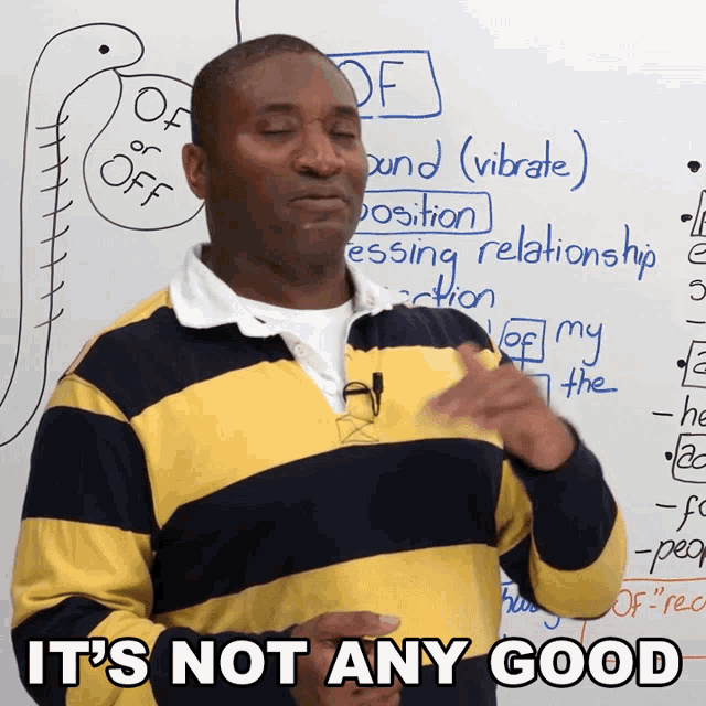 a man in a yellow and black striped shirt says it 's not any good in front of a whiteboard