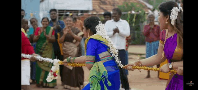 a group of women are playing tug of war with ropes in front of a crowd of people .