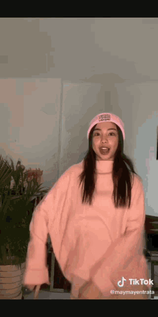 a woman is wearing a pink sweater and a pink hat .