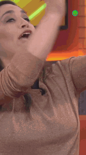 a woman is sitting on an orange couch with her hands in the air in front of a tv screen that says bateman