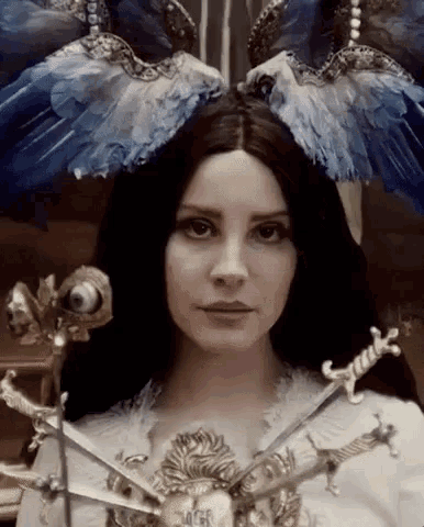 a woman with long black hair is wearing a blue and white feathered headpiece with swords .