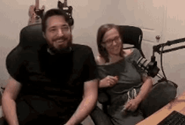 a man and woman are sitting in front of a microphone in a room .