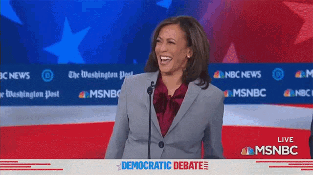 a woman laughs while standing in front of a msnbc banner