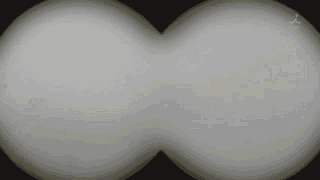 a pair of binoculars with a black background and a reflection of a person in the lenses .