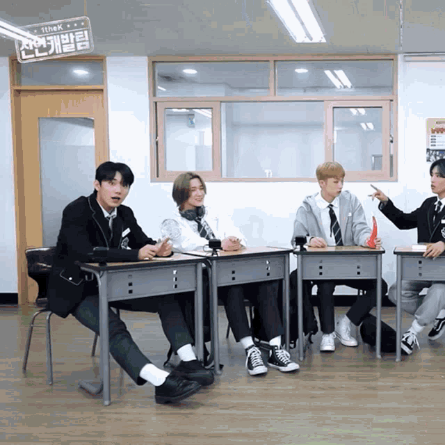 a group of young men are sitting at desks in a classroom with a sign that says think