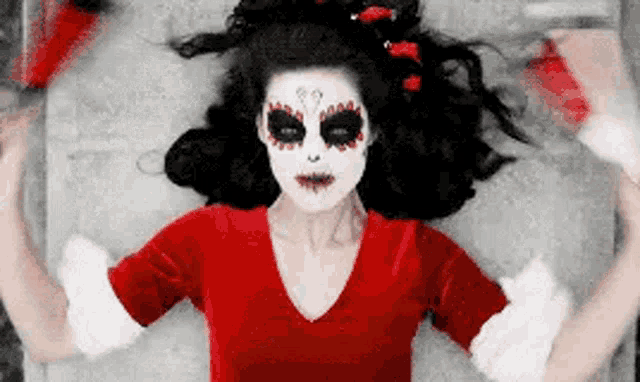 a woman in a day of the dead costume is laying on the floor .