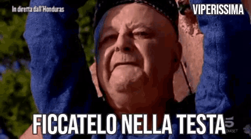 a man is holding his arms up in the air with the words ficcatolo nella testa written on the bottom .