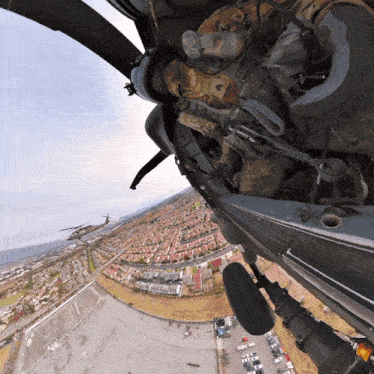 a man in a military uniform is flying a helicopter over a residential area