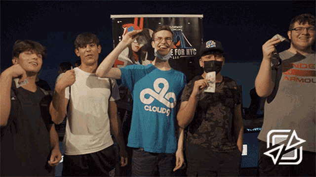 a man wearing a blue shirt that says cloud 9 stands in front of a sign that says e for nyc