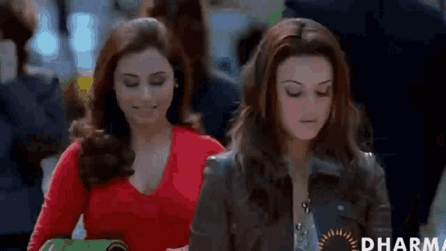two women are walking down a street and one is wearing a red shirt