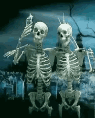 two skeletons are standing next to each other in a cemetery holding a cell phone .