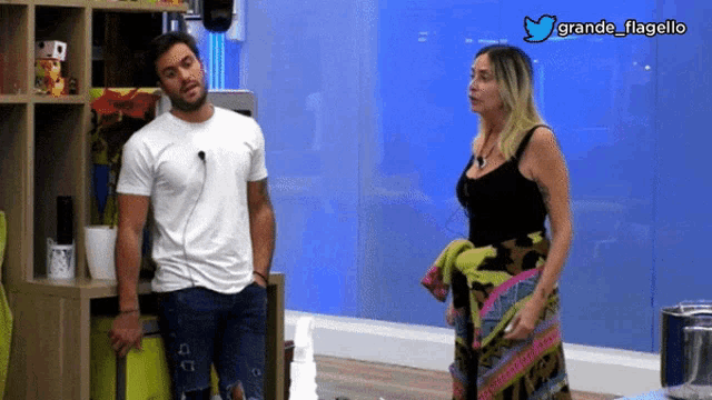 a man and a woman are standing in front of a blue wall with the hashtag grande flagello on the bottom