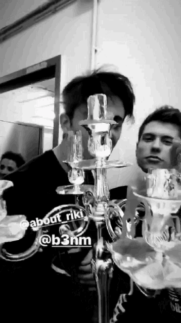 a black and white photo of a man standing next to a candle holder with the name about riki on it