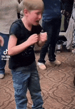a young boy is dancing in front of a crowd of people .