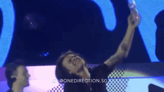 a man is taking a selfie on stage while holding a bottle of water .