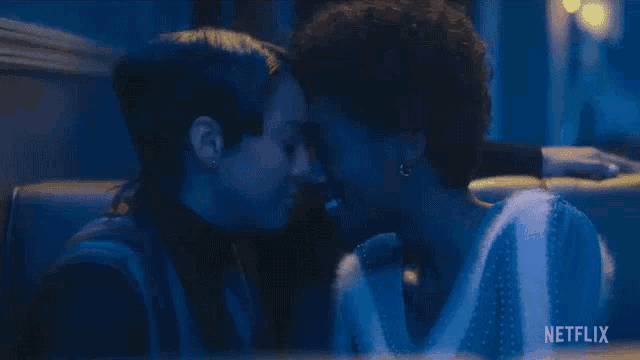 two women are kissing in a dark room with a netflix logo in the background .