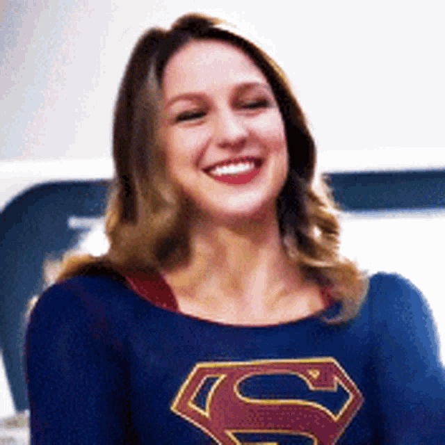 a woman in a superman costume is smiling and looking at the camera .