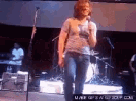 a man is singing into a microphone while standing on a stage .