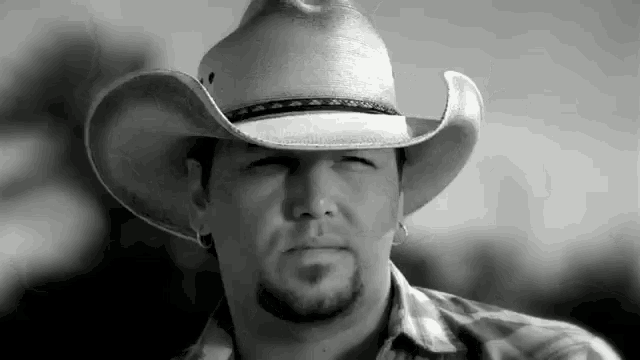 a black and white photo of a man wearing a cowboy hat and a plaid shirt .