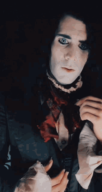 a man with blue eyes and a scarf around his neck looks at the camera