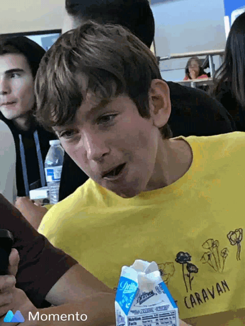 a young boy wearing a yellow shirt with the word caravan on it