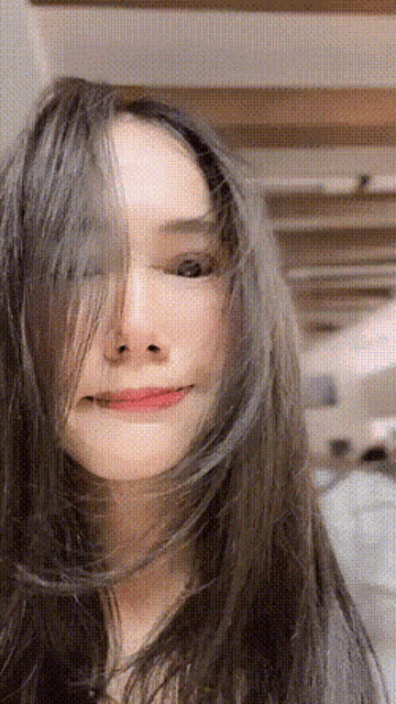 a woman with long hair looks at the camera