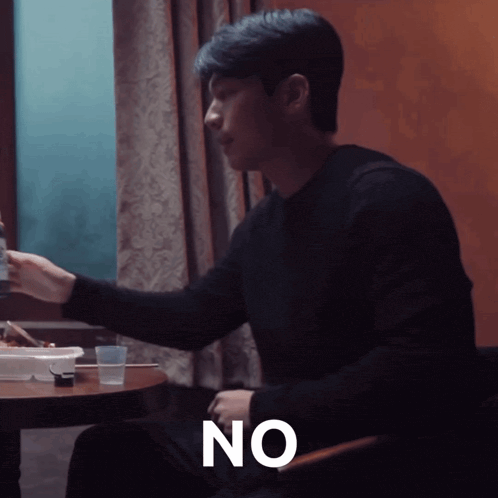 a man sitting at a table with the word no written on his chest