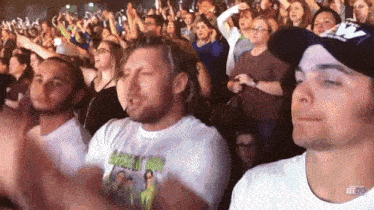 a crowd of people at a concert with a man wearing a t-shirt that says ' green day ' on it