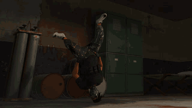 a person is doing a handstand in a room with green lockers and barrels