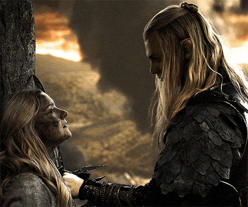 a man with long blonde hair is holding a woman 's neck