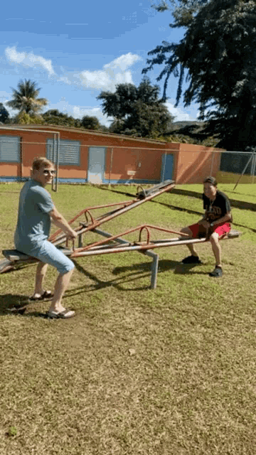 two boys are playing on a seesaw with one wearing a t-shirt that says ' sd ' on it