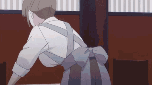 a woman in an apron is standing next to a table in a room .